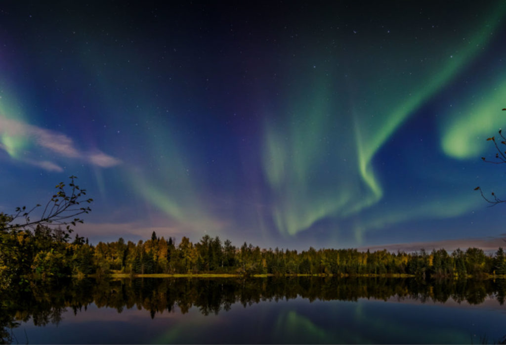 Aurora over a lake in Alaska, at sunset